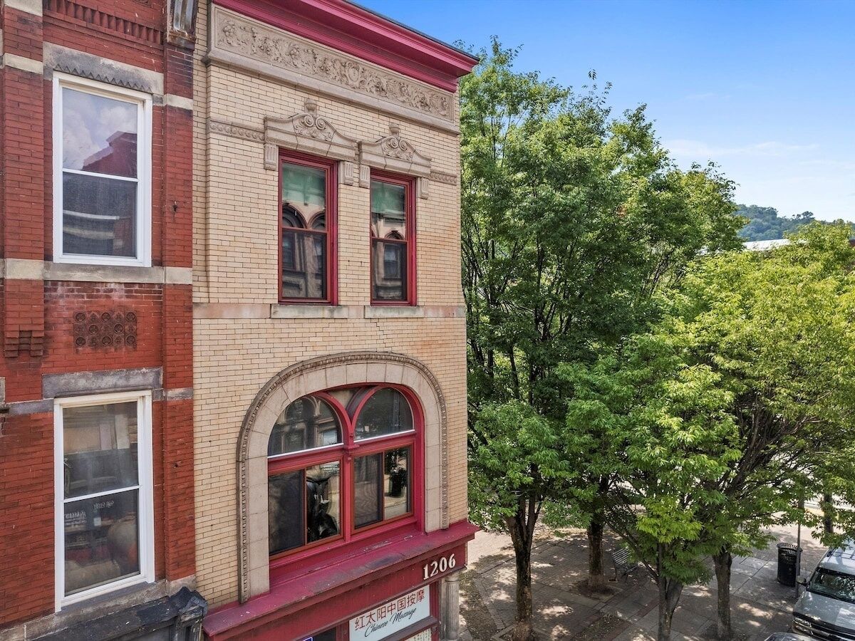 A two-story building with a red brick facade and a large arched window on the ground floor.