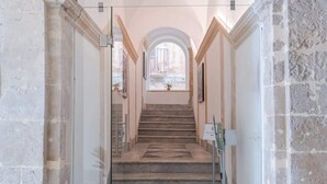 A grand staircase with marble steps and a geometric tile pattern at the bottom, leading to an arched doorway. - Palazzo Pupillo Liberty Suite (Syracuse)