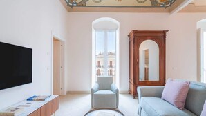 A modern living room with a flat-screen TV, a sofa, a chair, and a coffee table. - Palazzo Pupillo Liberty Suite (Syracuse)