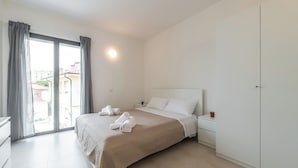 Quarto com cama, mesa de cabeceira, guarda-roupa e janela com cortinas.