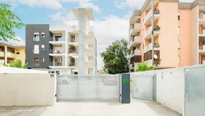 Um complexo residencial fechado com vários edifícios de apartamentos, céu claro e uma árvore ao fundo.