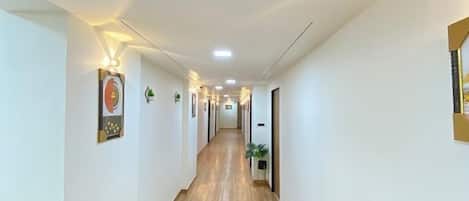 Un largo y estrecho pasillo con piso de madera y paredes blancas.