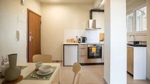 Une cuisine compacte comprenant un coin repas, un petit réfrigérateur et une machine à café.