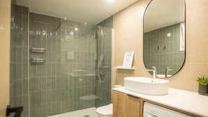 Une salle de bain moderne avec une douche à parois de verre, un lavabo avec un miroir et un lave-linge.