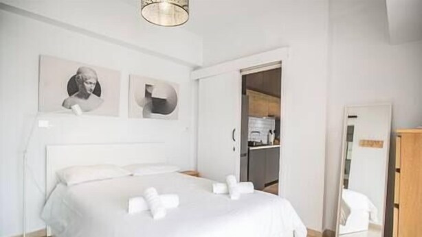 Un dormitorio ordenado con una cama grande, una mesita de noche, una lámpara de pie y un armario.