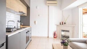 Una cocina moderna con gabinetes grises, horno integrado y salpicadero de azulejos blancos.