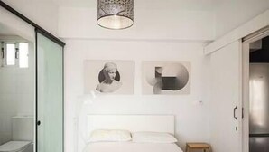 Un dormitorio moderno con una cama grande, cabina de ducha de vidrio y diseño minimalista.