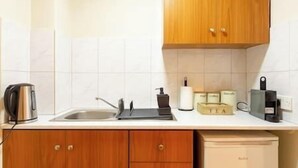 Een keuken met een spoelbak, waterkoker, theedoos en koffieapparaat.