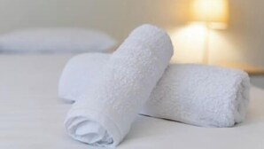 Twee opgerolde witte handdoeken op een bed.