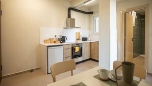Una cocina compacta con electrodomésticos modernos, una mesa de comedor con sillas y un horno a la vista.