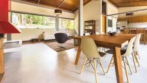 Un vaste espace dédié à la salle à manger, avec une longue table en bois, plusieurs chaises et un luminaire suspendu moderne.