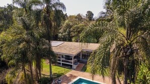Une maison avec une piscine, entourée d’une végétation luxuriante.