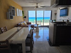 A dining area with a table and chairs, a sofa, a TV, and a kitchen area with a stove.