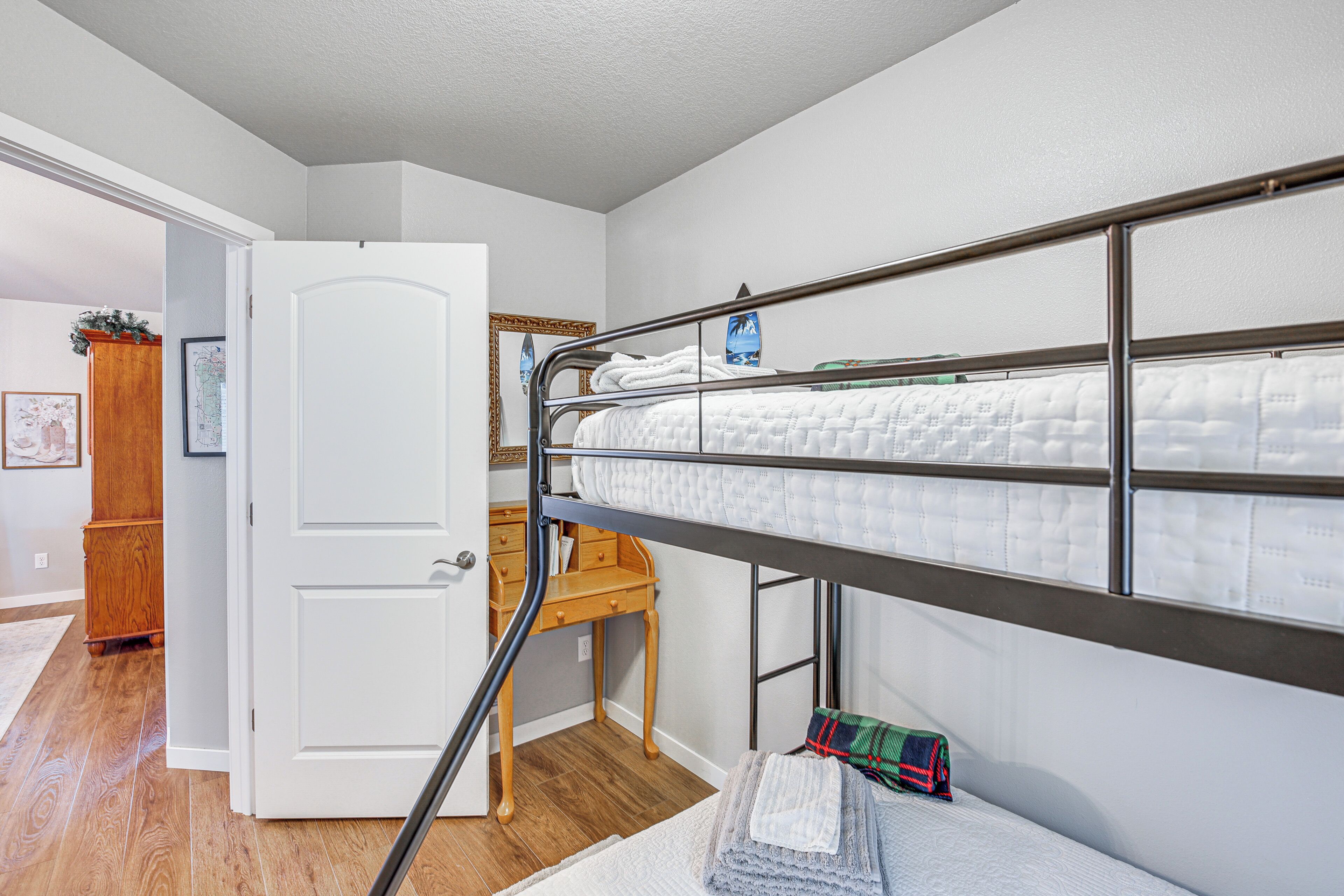 A bunk bed with a metal frame, a wooden chair, and a white door.