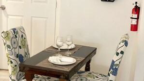 A dining table with floral chairs, a fire extinguisher on the wall, and hexagonal wall decorations.