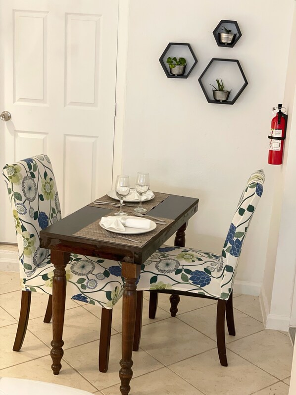 Uma mesa de jantar com cadeiras florais, um extintor na parede e decorações hexagonais.