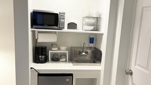 A compact kitchenette with a microwave, coffee maker, sink, and refrigerator.