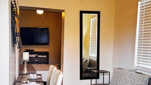 Ein kompakter Wohnbereich mit Essbereich, einer Couch, einem Deckenventilator und einem an der Wand befestigten Flachbildfernseher.