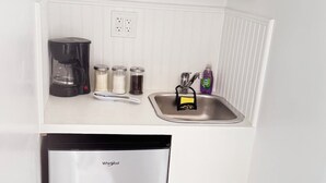 Eine kleine Küche mit Mikrowelle, Kaffeemaschine und Kühlschrank.