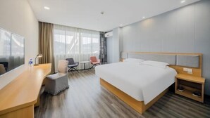 Una moderna camera d'albergo con un letto grande, una scrivania, una sedia e un piccolo tavolino.