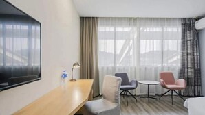 Una camera d'albergo con un letto, una scrivania, una sedia, un tavolino e una televisione.
