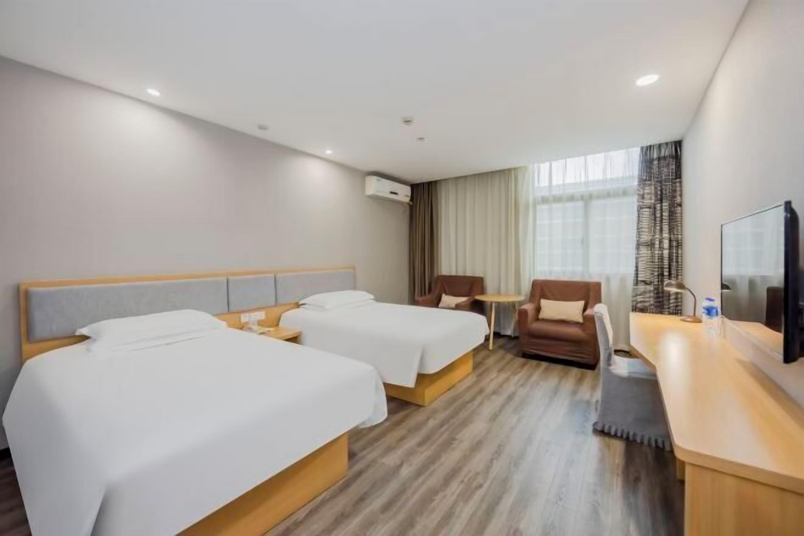Une chambre d’hôtel avec deux lits, un bureau, une chaise et un téléviseur.