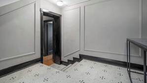 A hallway with a tiled floor, a staircase, and a door leading to another room. - The Burrow at Wrigley (Chicago)