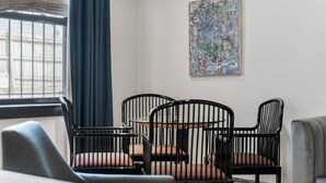 A corner room with a dining table and chairs, a window with curtains, and a piece of abstract art on the wall. - The Burrow at Wrigley (Chicago)