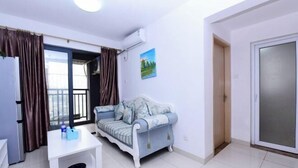 A compact living space with a sofa, a small table, and a door leading to a balcony. - Shenzhen Jintaoyuan Hotel Apartment (Shenzhen)