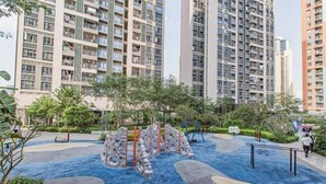 A playground with climbing structures and a blue rubberized surface, surrounded by greenery and residential buildings. - Shenzhen Jintaoyuan Hotel Apartment (Shenzhen)