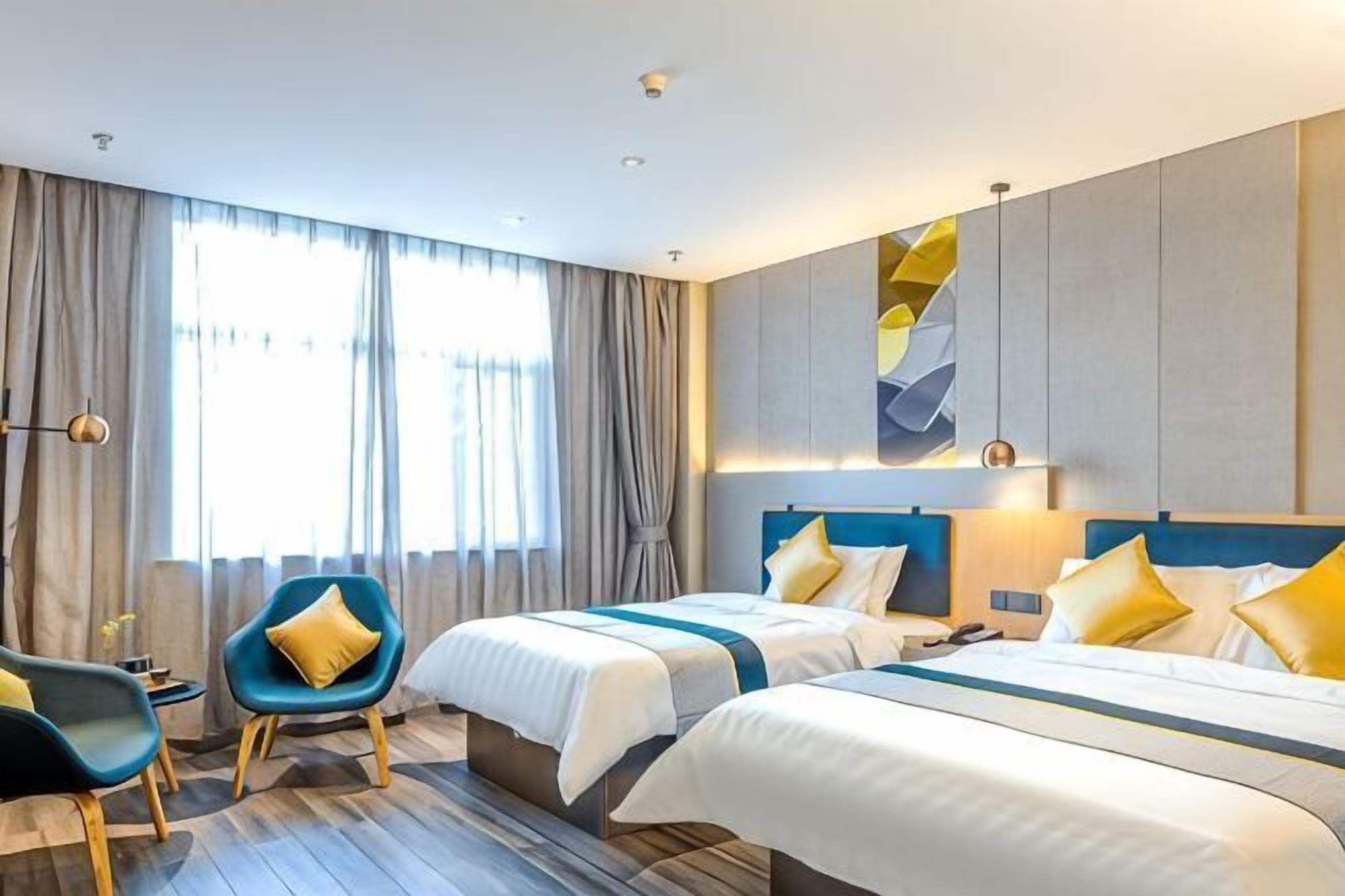 A hotel room with two beds, a desk, a chair, and a large window with curtains.