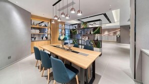 Un espace de salle à manger moderne avec une table en bois, des chaises bleues et des luminaires suspendus.