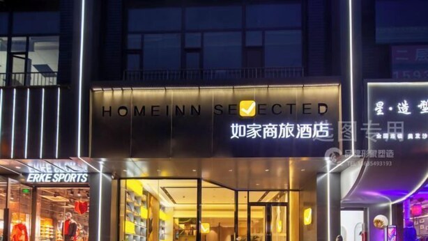 L’entrée d’un hôtel au design moderne, avec une façade en verre et une enseigne lumineuse.