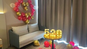 Une pièce avec un canapé, une table sur laquelle sont disposés des chiffres lumineux et des ballons formant un cœur.
