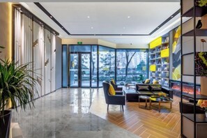 A modern lobby with a glass door entrance, a seating area with a sofa and armchairs, and a bookshelf with yellow and black decor. - Homeinn Selected Hotel (Taiyuan Changfeng Street Bingzhou South Road Taihang) (Taiyuan)