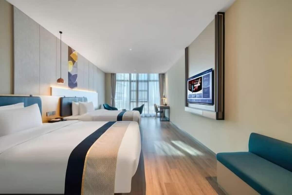 A hotel room with a large bed, a sofa, a desk, and a TV.