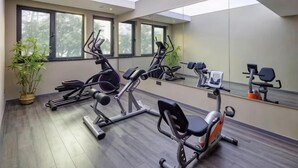 Une salle de sport équipée de matériel d’exercice, dotée de grandes fenêtres et d’un miroir.