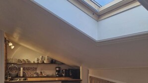 A compact kitchen with a skylight, wooden cabinets, and a built-in dishwasher. - Cosy room with minikitchen in charming Miðvágur, close to the airport. (Miðvágur)