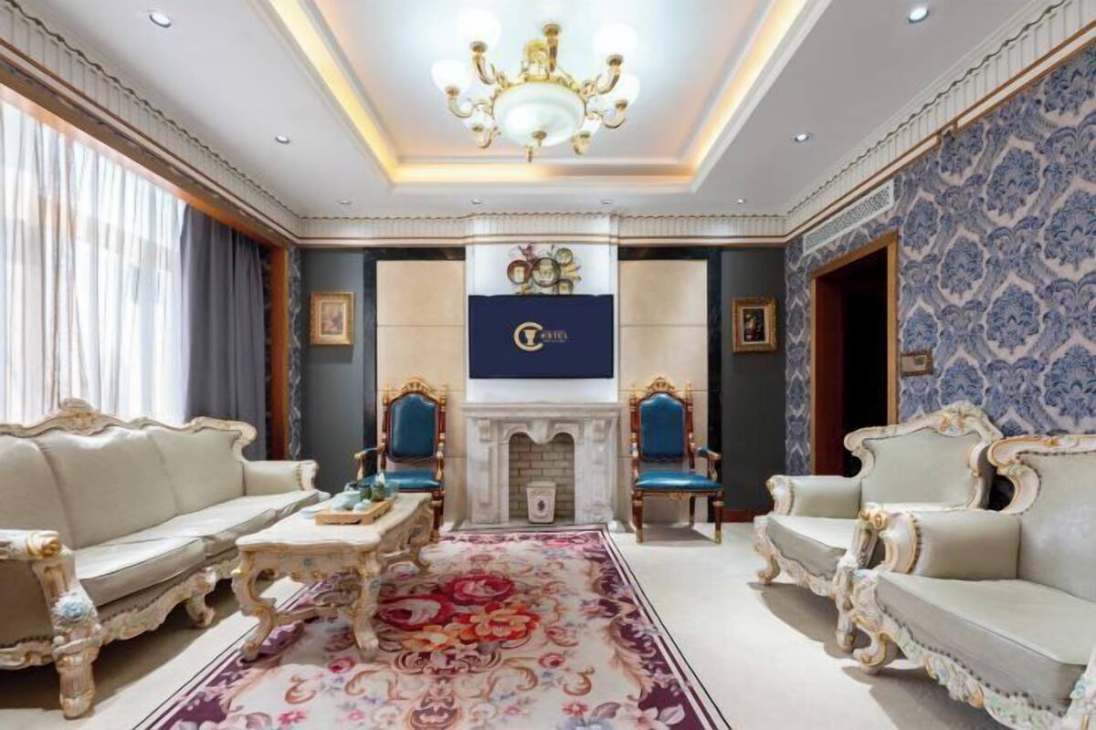 A luxurious hotel room with ornate furniture, a fireplace, and a chandelier.