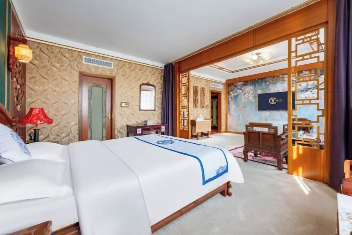 A hotel room with two beds, a wooden partition, a desk, and a chair.