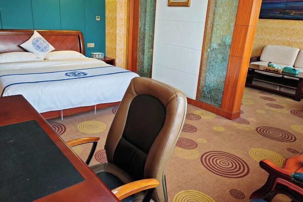 Een hotelkamer met een bed, een bureau, een stoel en een bank.
