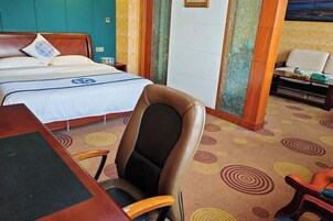 Una habitación de hotel con cama, escritorio, silla y sofá.