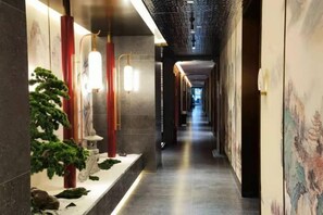 A corridor with a long, narrow layout, featuring a series of traditional-style lanterns and a bonsai tree on the left side. - Qiquan Ciyue Art Hotel (Zibo Songling Former Residence) (Zibo)