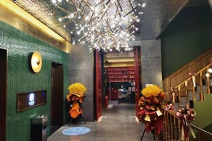 A hotel lobby with a modern chandelier, a reception desk, and decorative floral arrangements. - Qiquan Ciyue Art Hotel (Zibo Songling Former Residence) (Zibo)