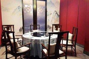 Une table ronde, des chaises, une nappe et un objet placé au centre.