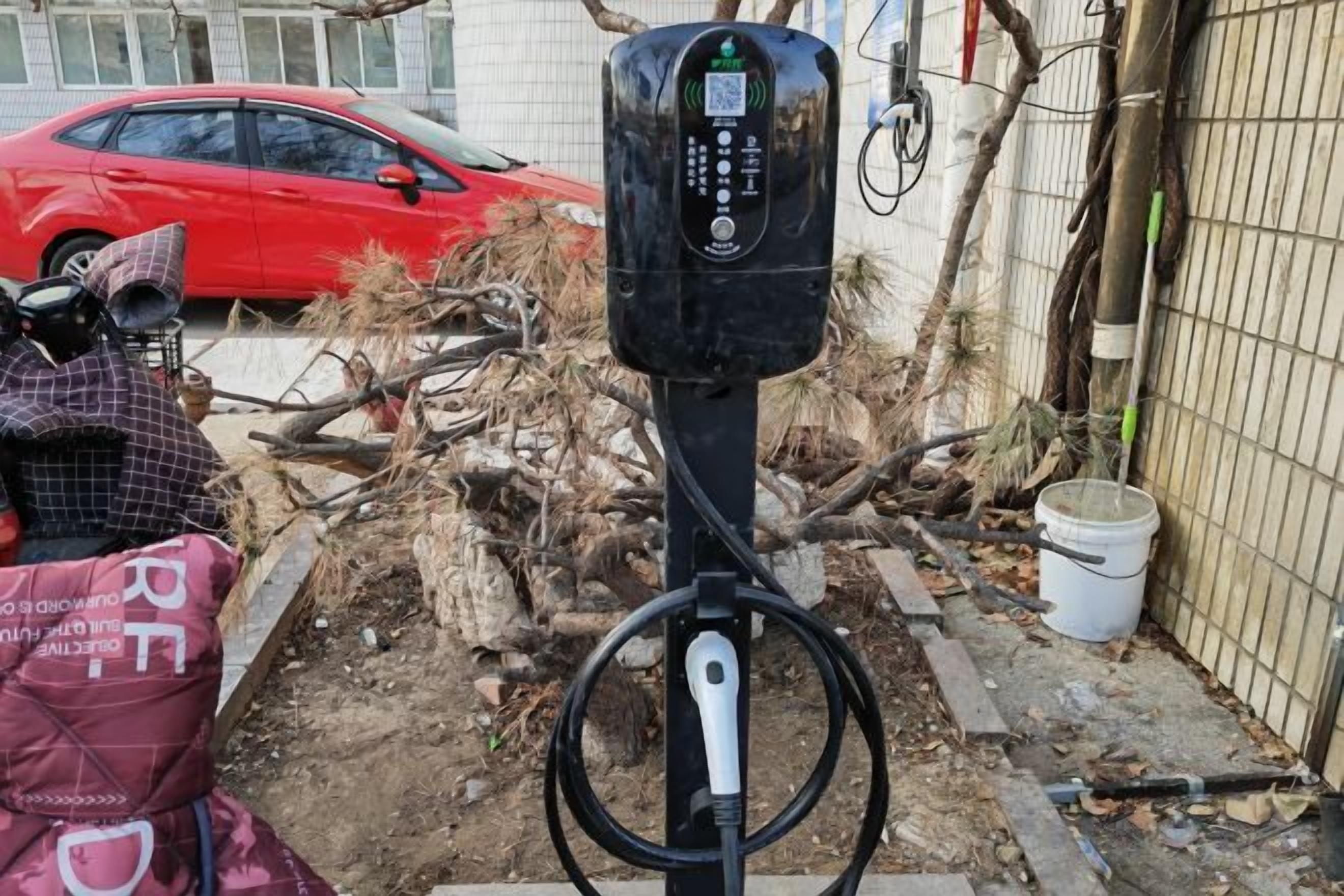 A parking meter with a red car in the background.