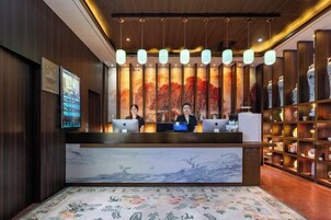 Un mostrador de recepción con pantalla digital, una alfombra floral grande y decoración tradicional.
