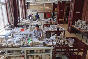 Taller de cerámica con mesas exhibiendo diferentes objetos de alfarería.