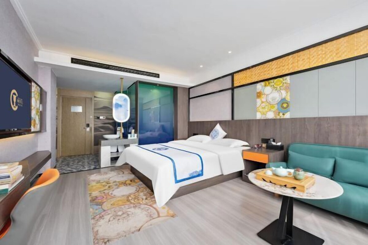 Een moderne hotelkamer met een bed, een bureau, een sofa en een klein tafeltje met een dienblad.