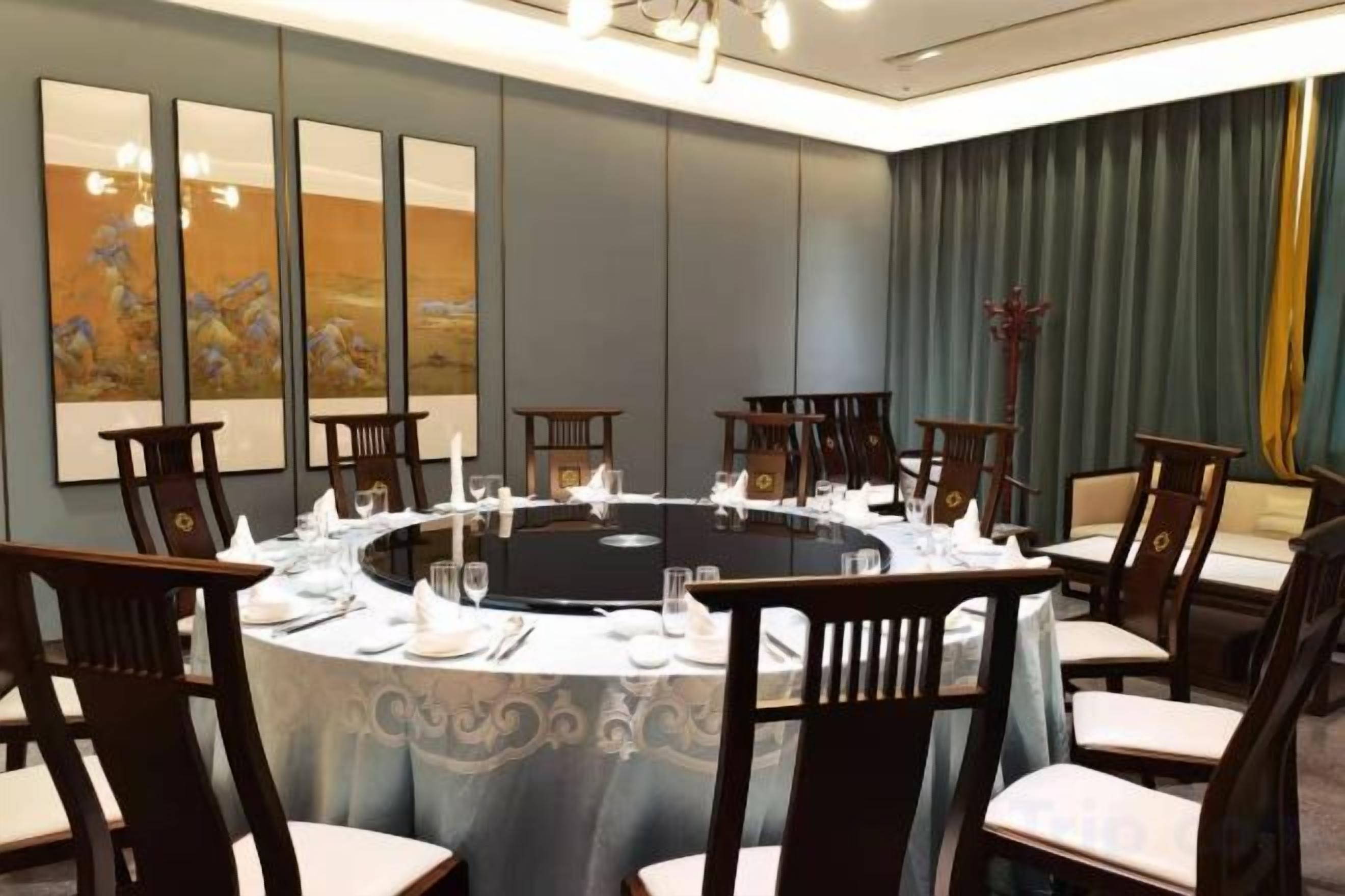 Un salón de conferencias con una mesa redonda, sillas y un mantel.